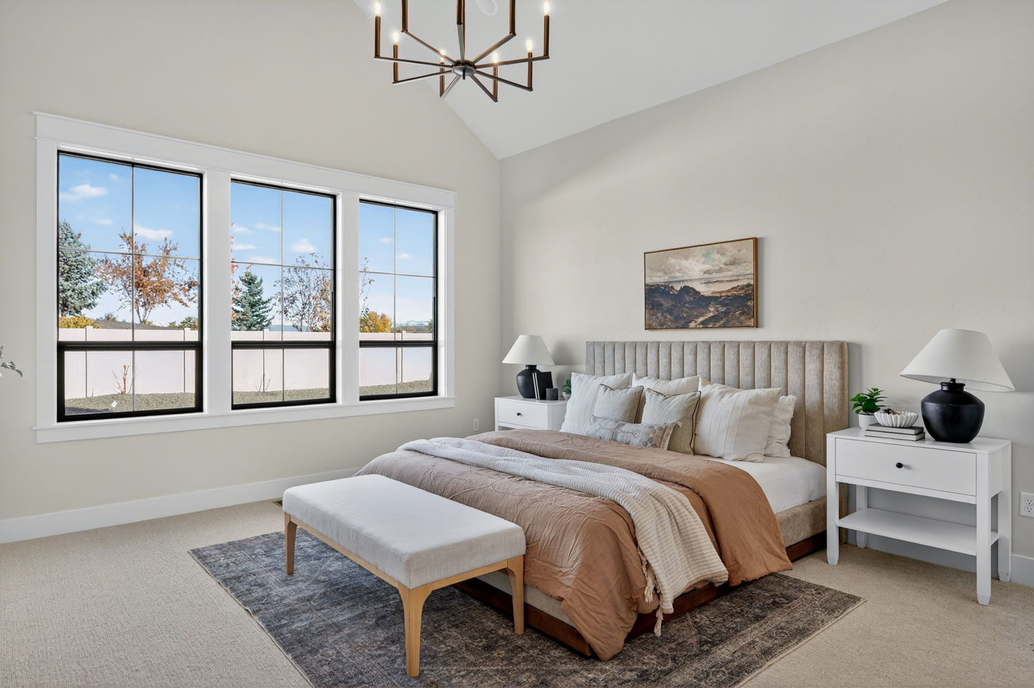 Spacious master bedroom with vaulted ceiling, modern sputnik chandelier, upholstered headboard, and neutral earth-tone bedding