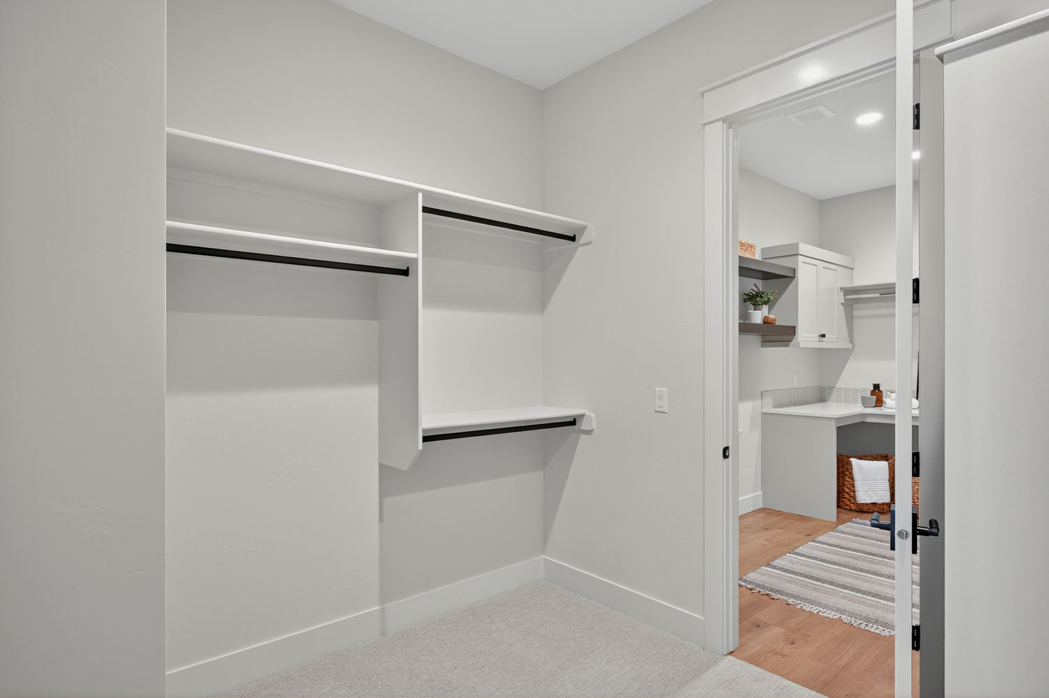 Spacious walk-in closet with built-in white shelving, black hanging rods, and direct access to laundry room