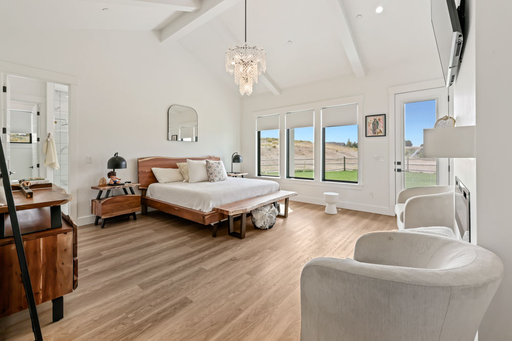 Spacious master bedroom interior with vaulted ceilings, chandelier, and Idaho hillside views