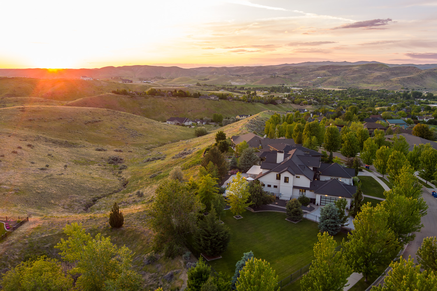 Aerial sunset view of hillside home with Boise foothills and mountain backdrop