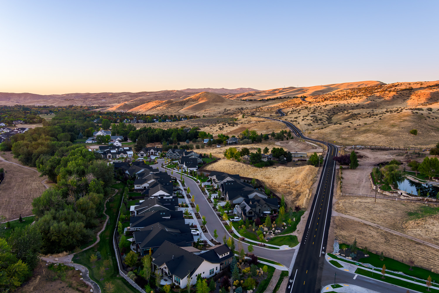 Aerial view of new Idaho subdivision with modern homes near golden foothills