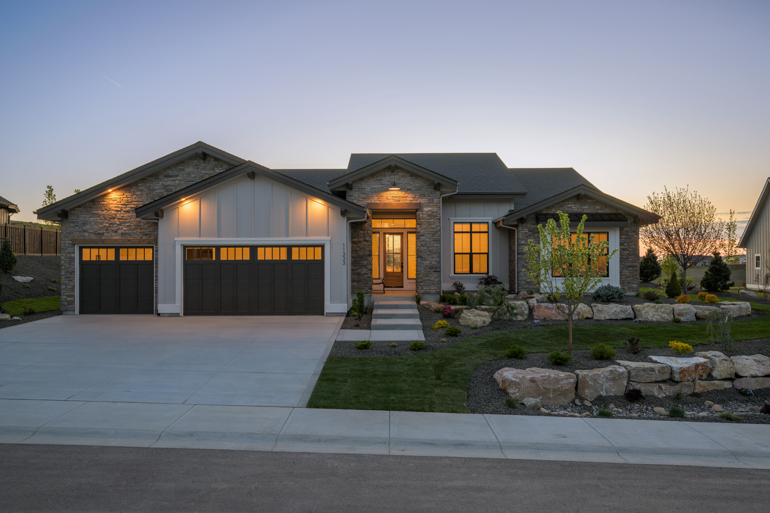 Contemporary home exterior with stone accents and covered entry at dusk in Boise Idaho