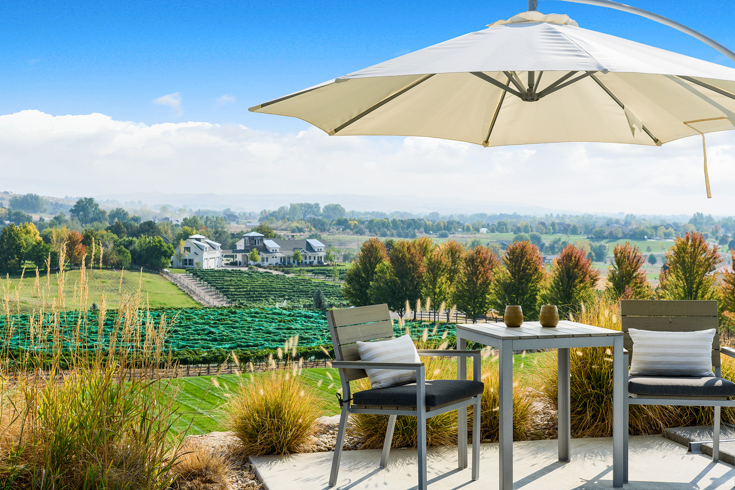Hilltop patio dining area with umbrella overlooking vineyard and valley views in Idaho