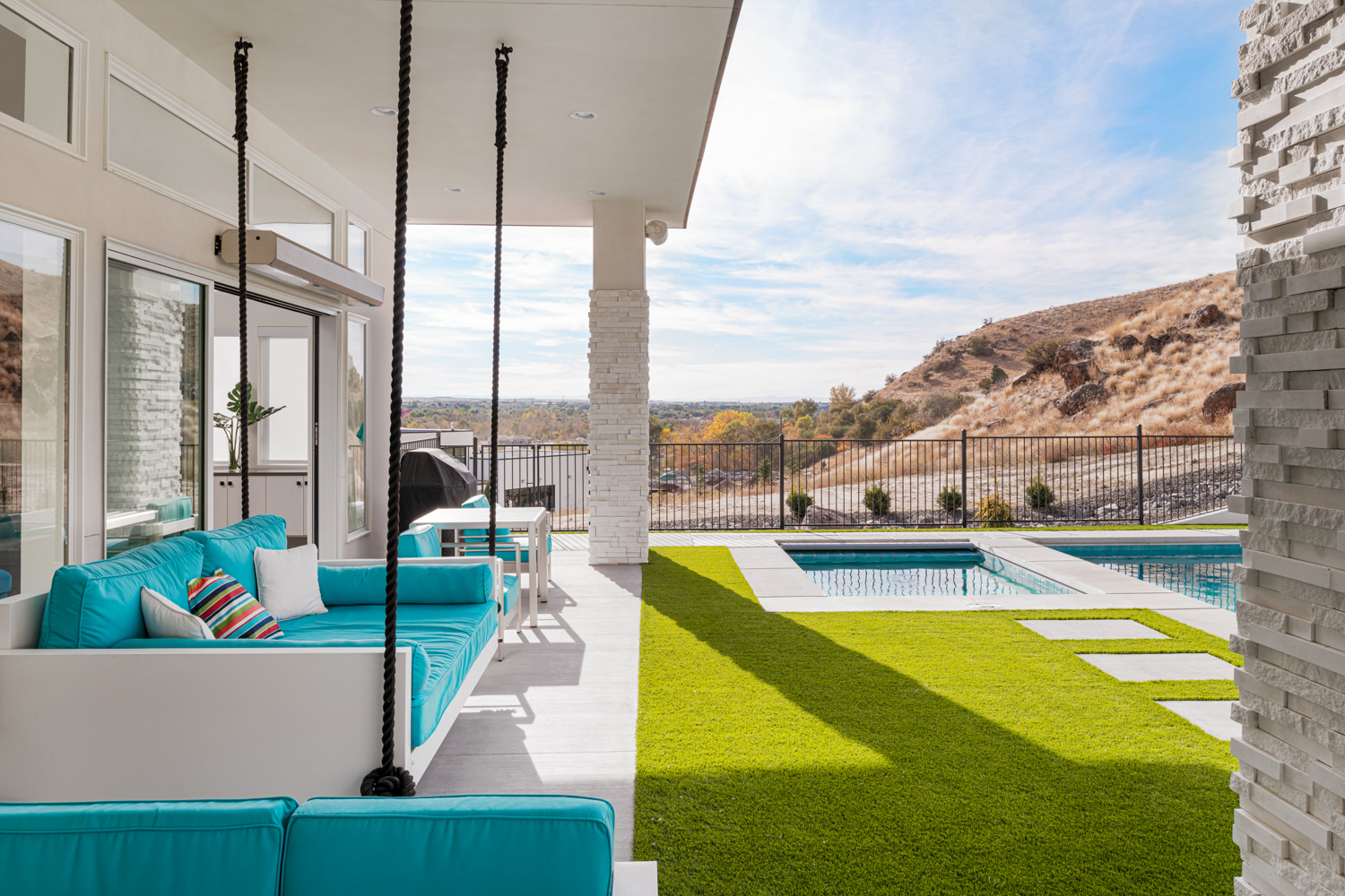 Covered patio with turquoise seating and infinity pool overlooking Boise foothills
