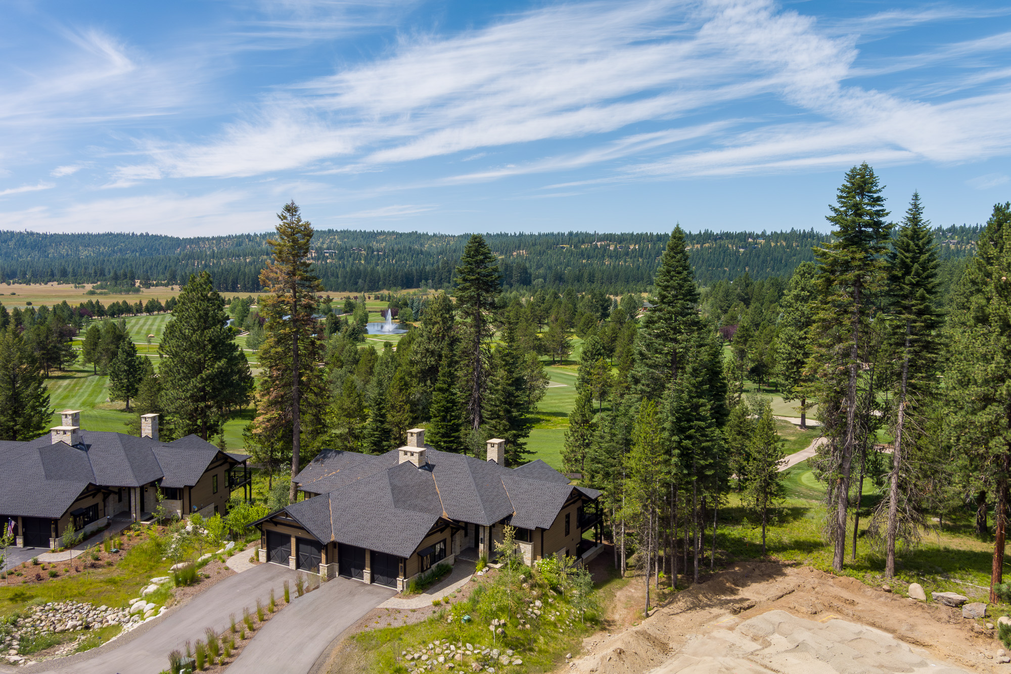 Aerial view of luxury homes among pines overlooking Idaho golf course with fountain