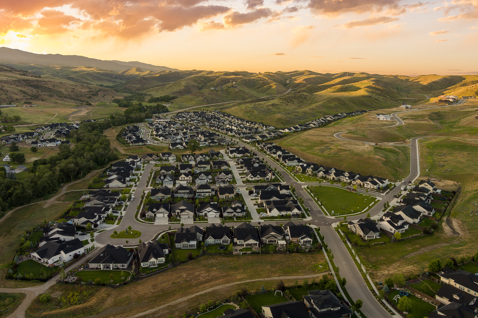 Aerial drone view of Idaho residential subdivision in rolling foothills at sunset