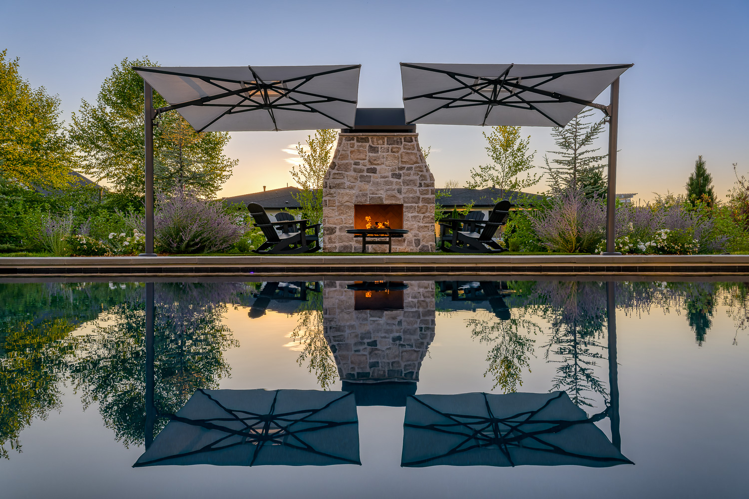 Rustic barn-style luxury home exterior at dusk with warm lighting in Eagle Idaho
