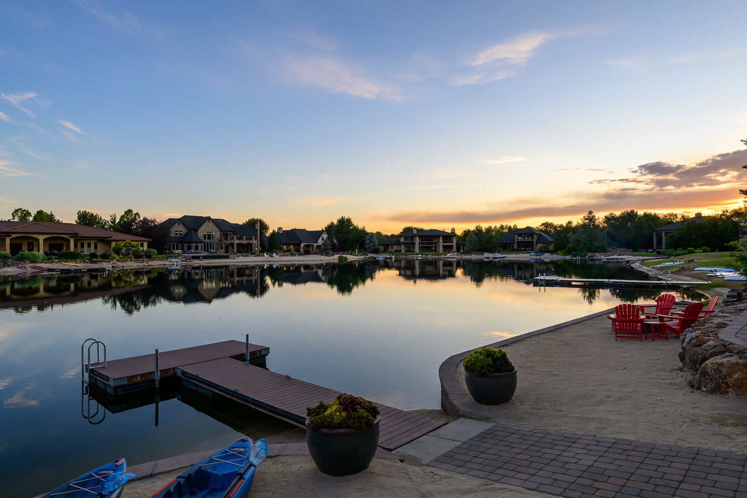 Luxury craftsman home with stone pillars and warm glow at twilight in Meridian Idaho