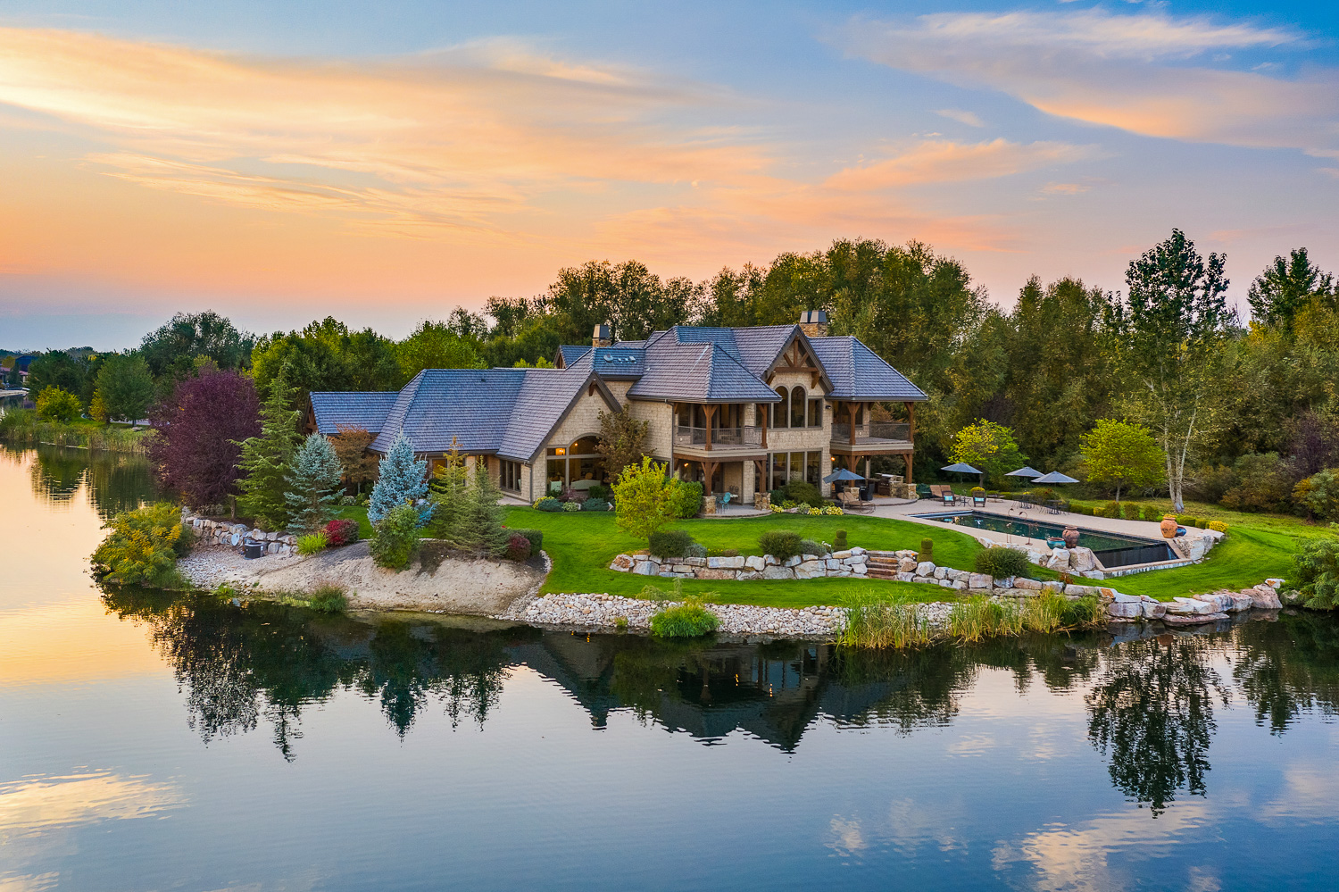 Luxury lakefront estate with pool, stone exterior, and sunset views in Boise Idaho