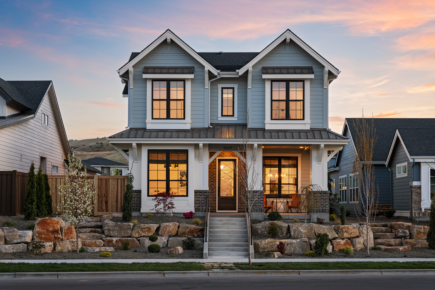 Two-story craftsman home exterior with covered porch and rock landscaping in Boise Idaho