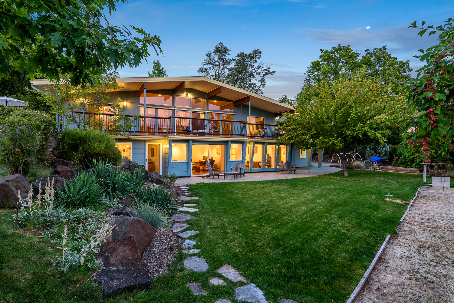 Mid-century modern two-story home exterior with landscaped backyard and bocce court in Boise Idaho