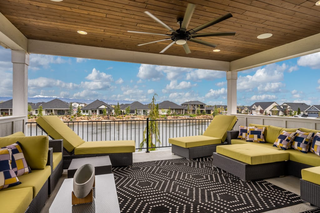 Exterior covered patio with lounge furniture, ceiling fan, and waterfront mountain views in Boise Idaho