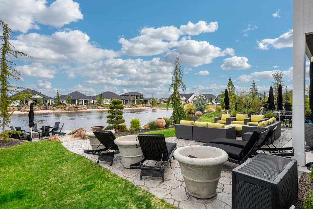 Exterior lakefront patio with lounge seating, landscaped yard, and waterfront views in Boise Idaho