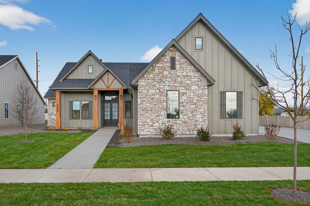 New construction modern farmhouse exterior with stone accent facade, wood timber entry, board-and-batten siding, and manicured front lawn
