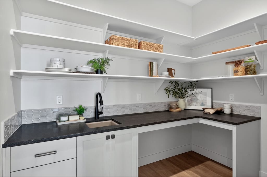 Walk-in butler pantry with dark granite countertops, white cabinetry, open shelving, hexagon tile backsplash, and matte black fixtures