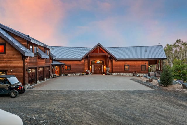 Exterior twilight view of luxury log home with metal roof and paver driveway near Boise Idaho