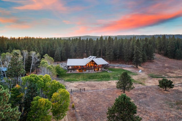 Aerial exterior view of mountain lodge on wooded acreage at sunset near Boise Idaho