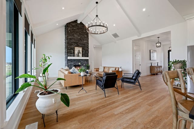 Spacious great room interior with vaulted ceiling, stacked stone fireplace, and chandelier in Boise Idaho