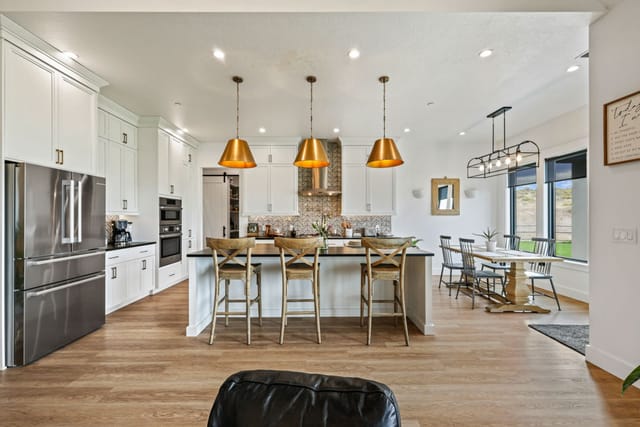 Open-concept interior kitchen with white cabinets, gold pendants, and dining area in Boise Idaho