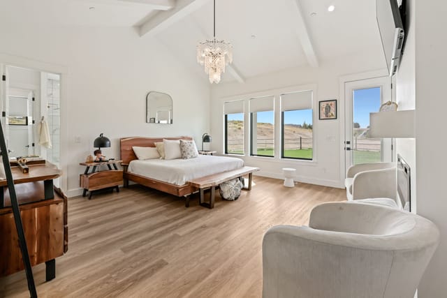 Spacious master bedroom interior with vaulted ceilings, chandelier, and Idaho hillside views
