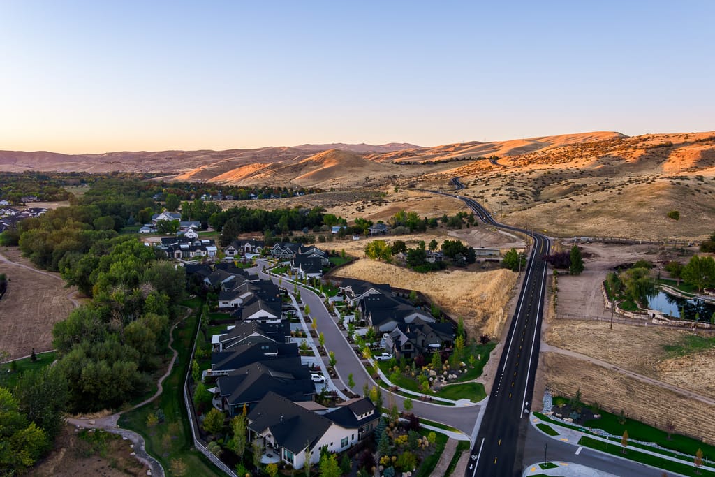 Aerial view of new Idaho subdivision with modern homes near golden foothills