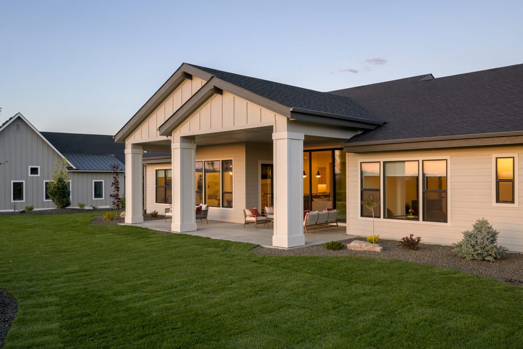 Luxury farmhouse exterior with warm interior lighting at twilight in Boise Idaho