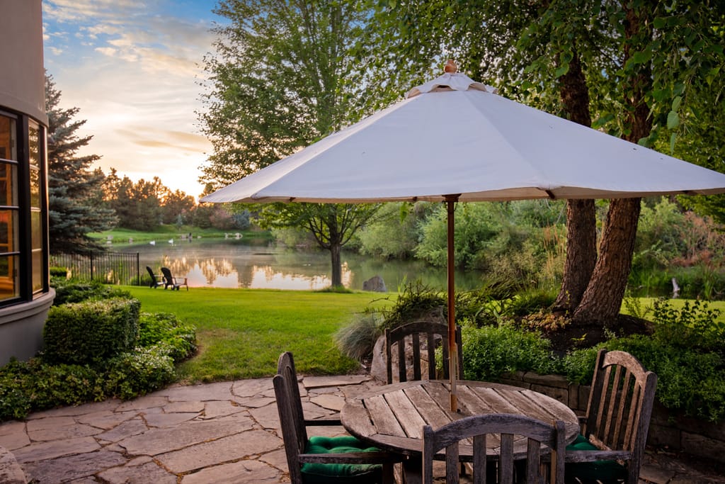 Outdoor patio with umbrella and Adirondack chairs overlooking lawn at sunset in Boise