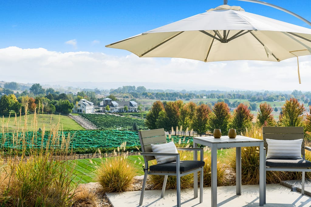 Hilltop patio dining area with umbrella overlooking vineyard and valley views in Idaho
