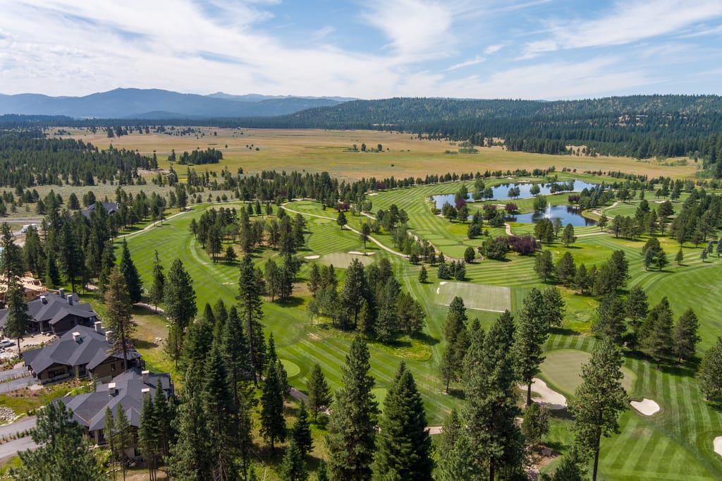 Aerial panorama of manicured Idaho golf course with water features and mountain views