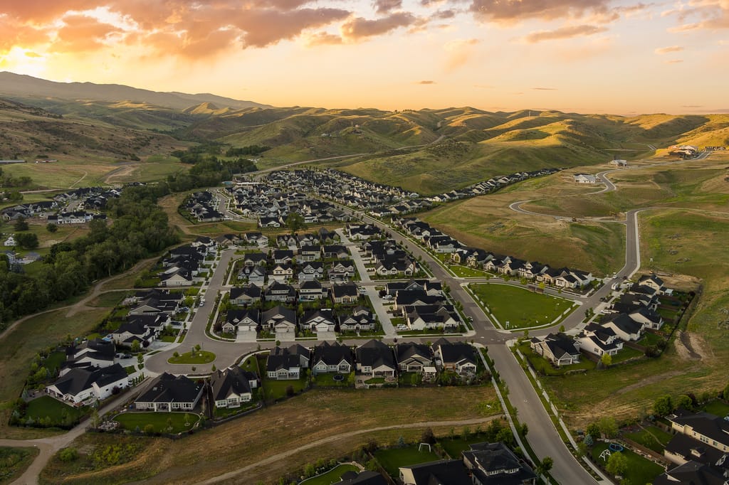 Aerial drone view of Idaho residential subdivision in rolling foothills at sunset